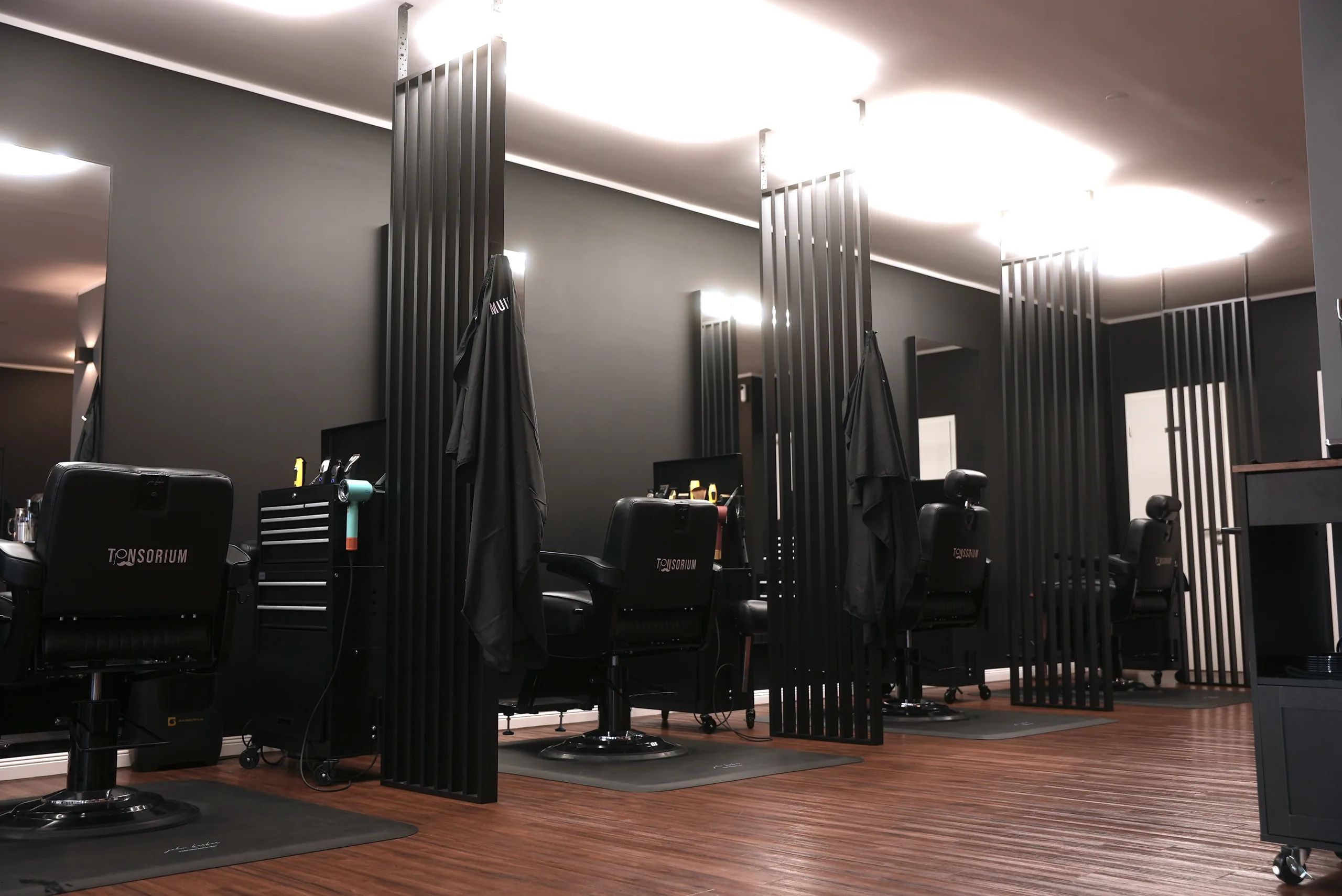 Arbeitsplätze mit schwarzen Barberstühlen und Lamellenwänden