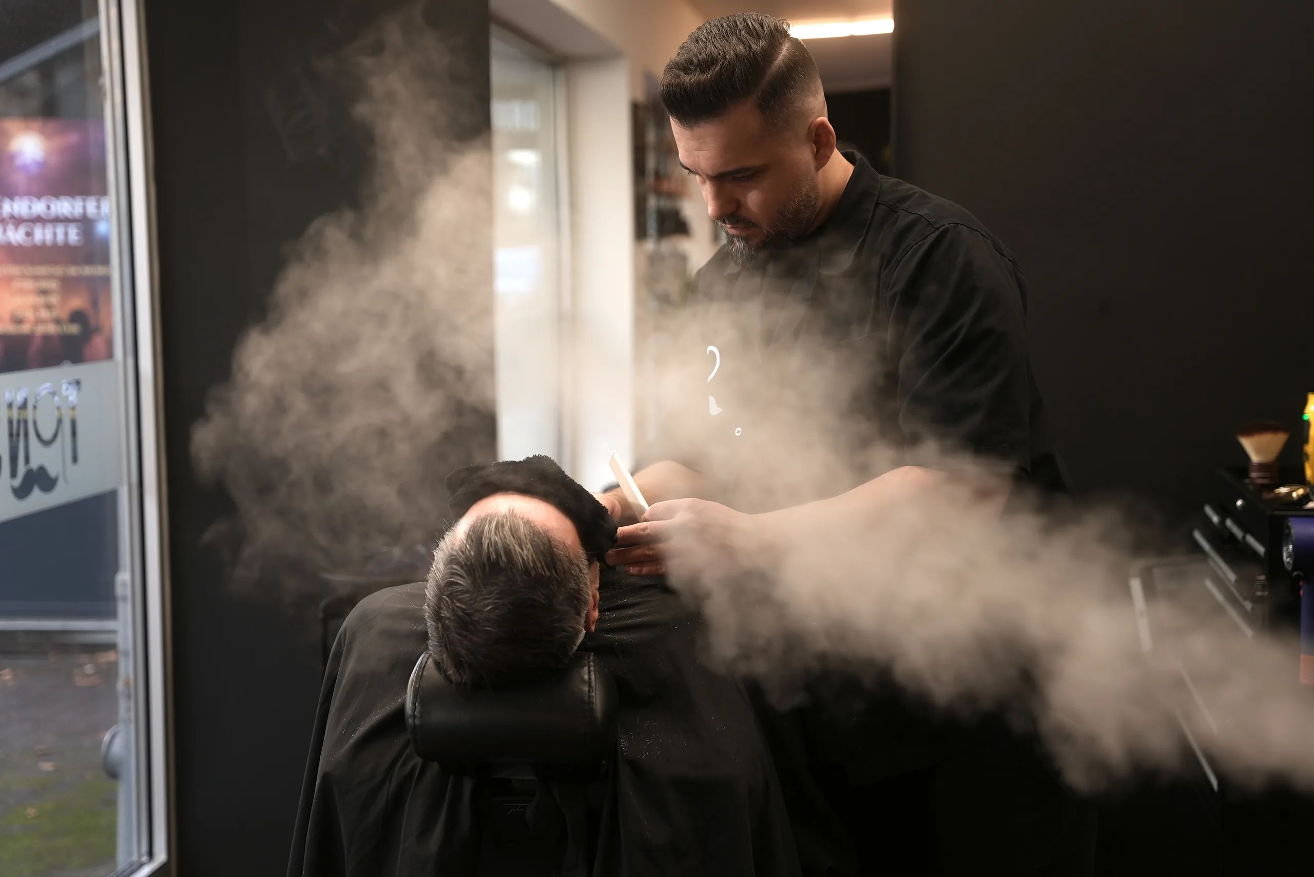 Barbier bei der Bartpflege mit warmem Dampf